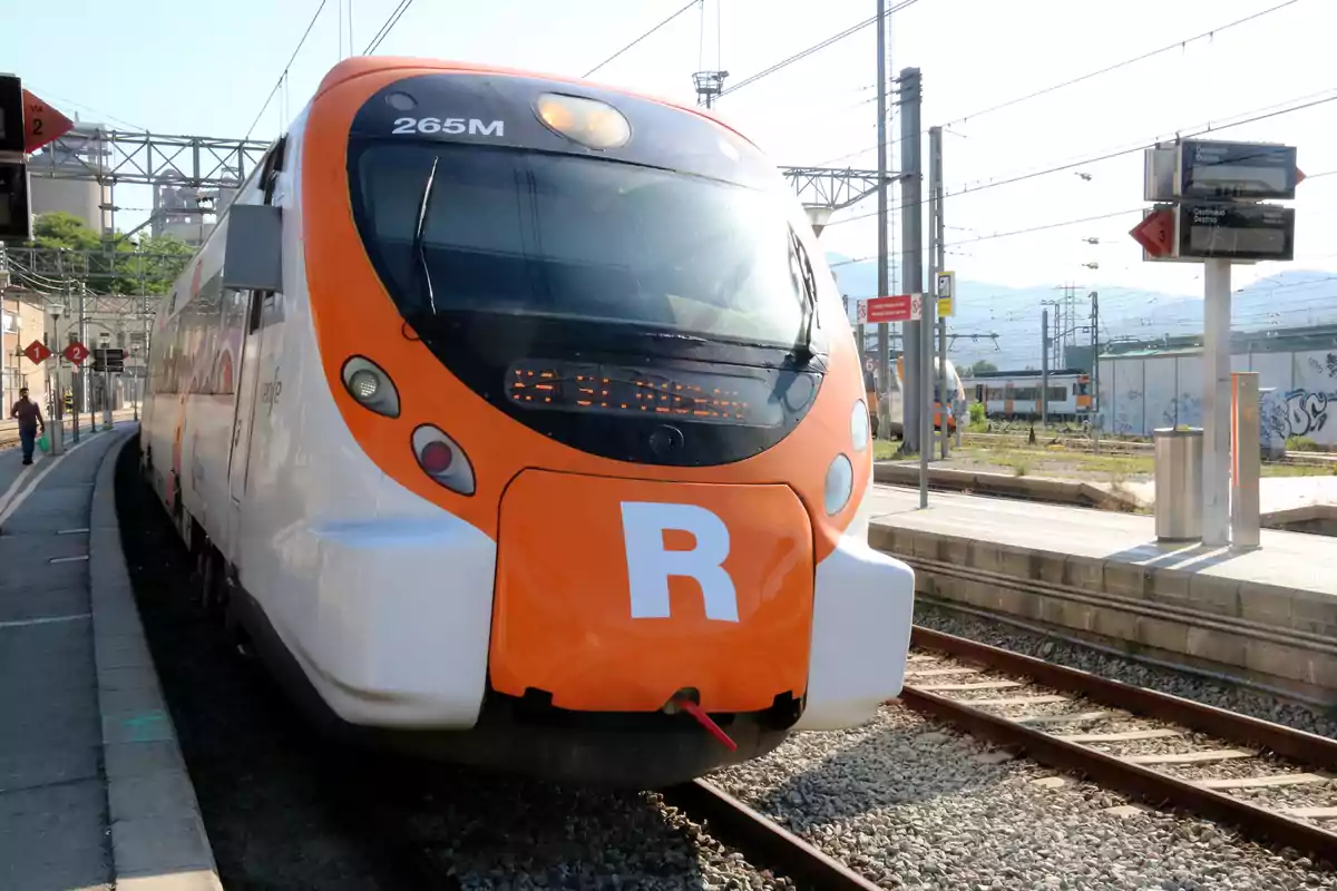 Un tren de cercanías en una estación con la letra "R" en el frente.