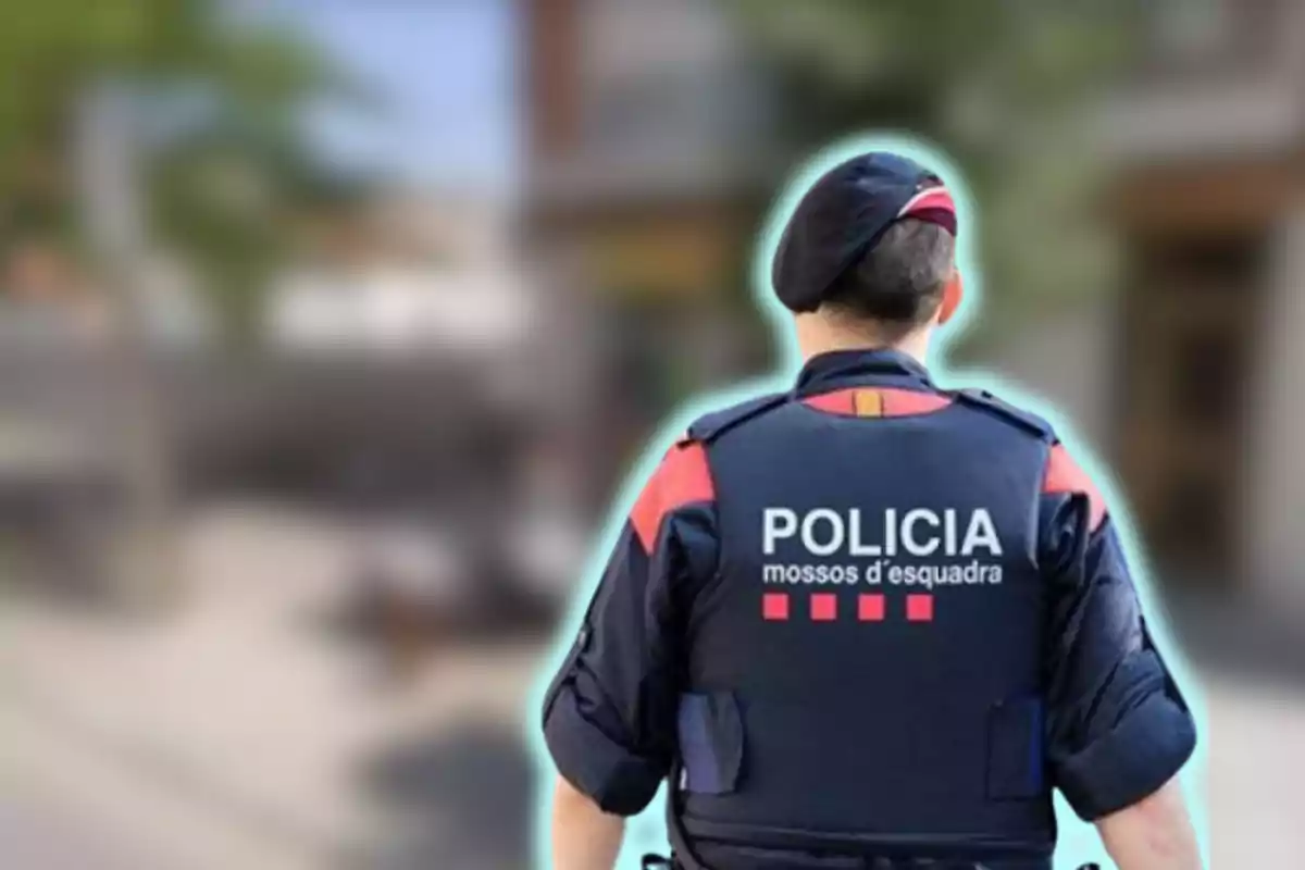 Policía de los Mossos d'Esquadra de espaldas con uniforme y boina en una calle desenfocada.