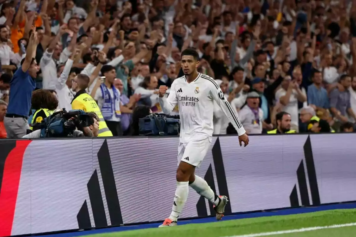 Un jugador de fútbol del Real Madrid celebra un gol mientras la multitud en las gradas lo vitorea.