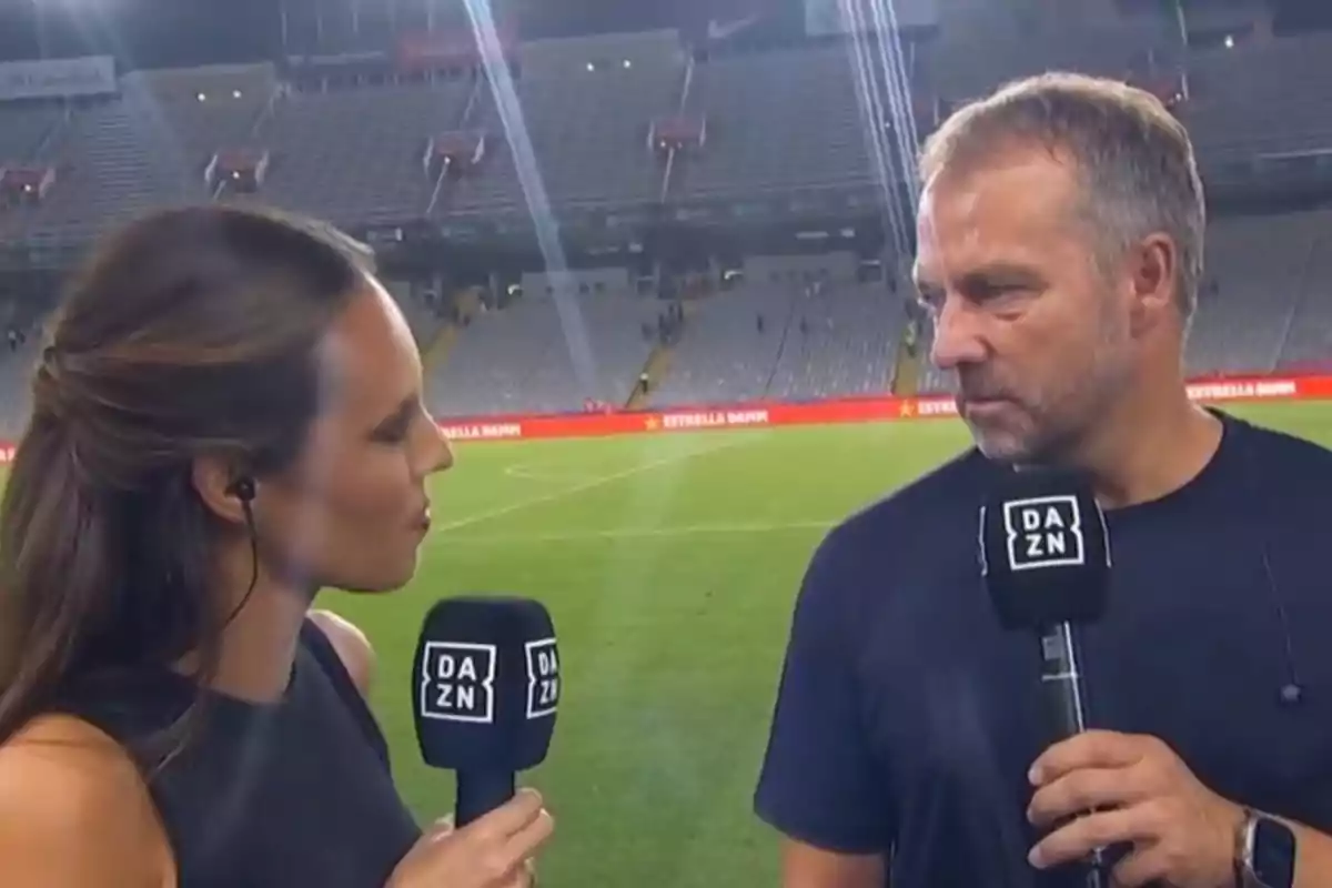 Dos personas están siendo entrevistadas en un estadio de fútbol, ambas sosteniendo micrófonos con el logo de DAZN.