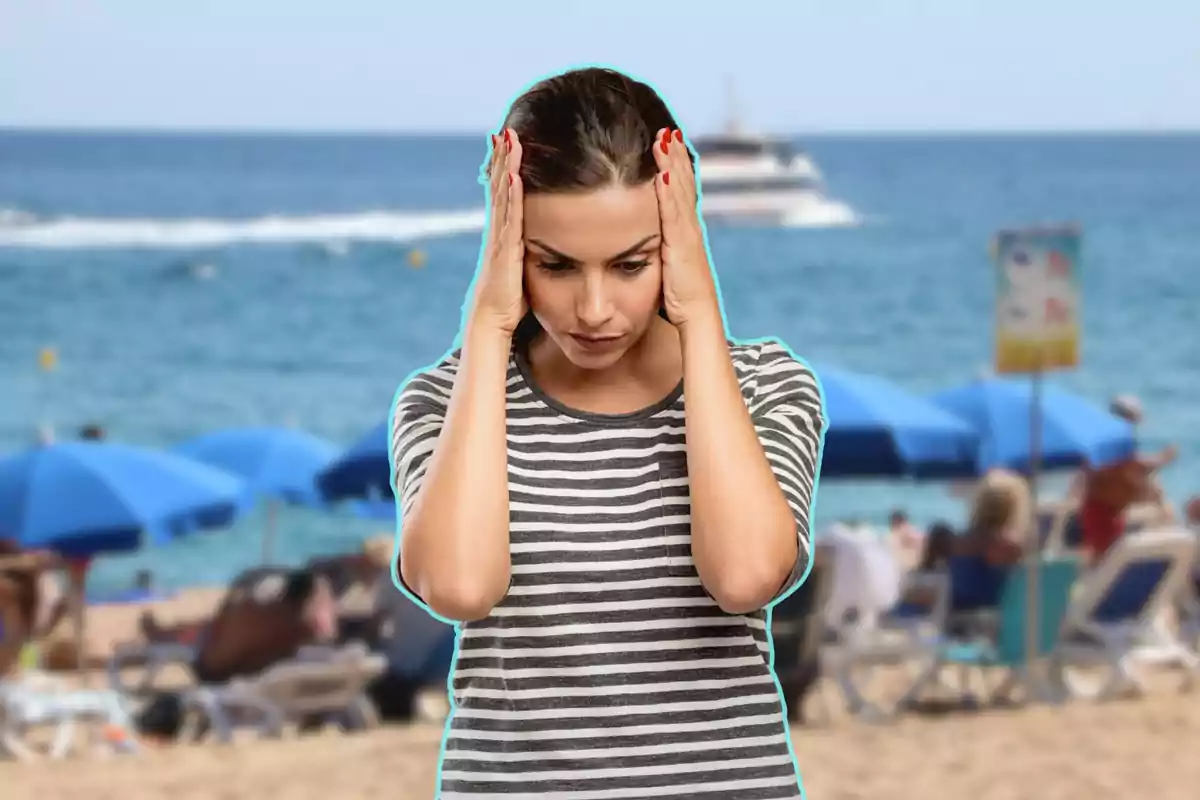 Mujer con camiseta de rayas sosteniendo su cabeza con las manos en una playa concurrida.