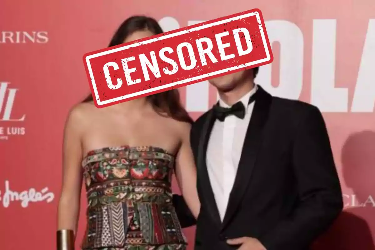 Dos personas posando en un evento con un cartel de "CENSORED" sobre sus rostros.