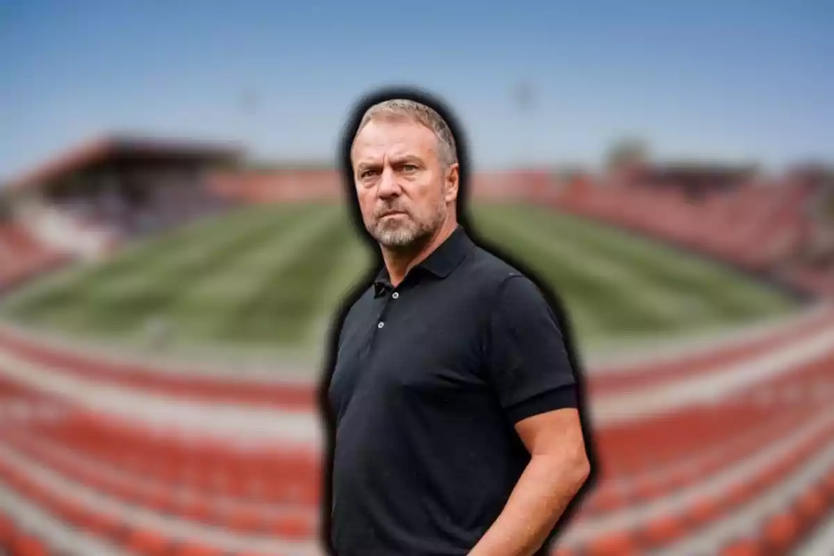 Hombre de pie en un estadio de fútbol con fondo desenfocado.