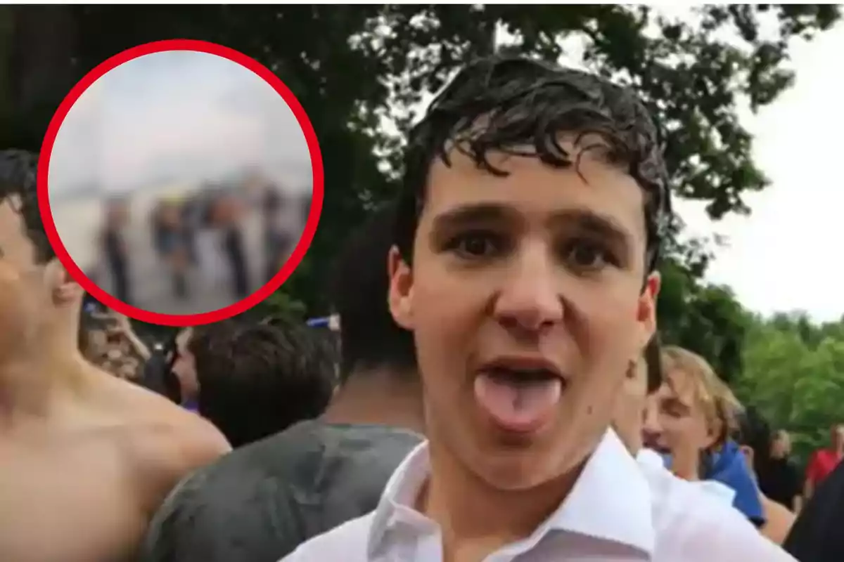 Un joven con la lengua afuera en un evento al aire libre, rodeado de otras personas.