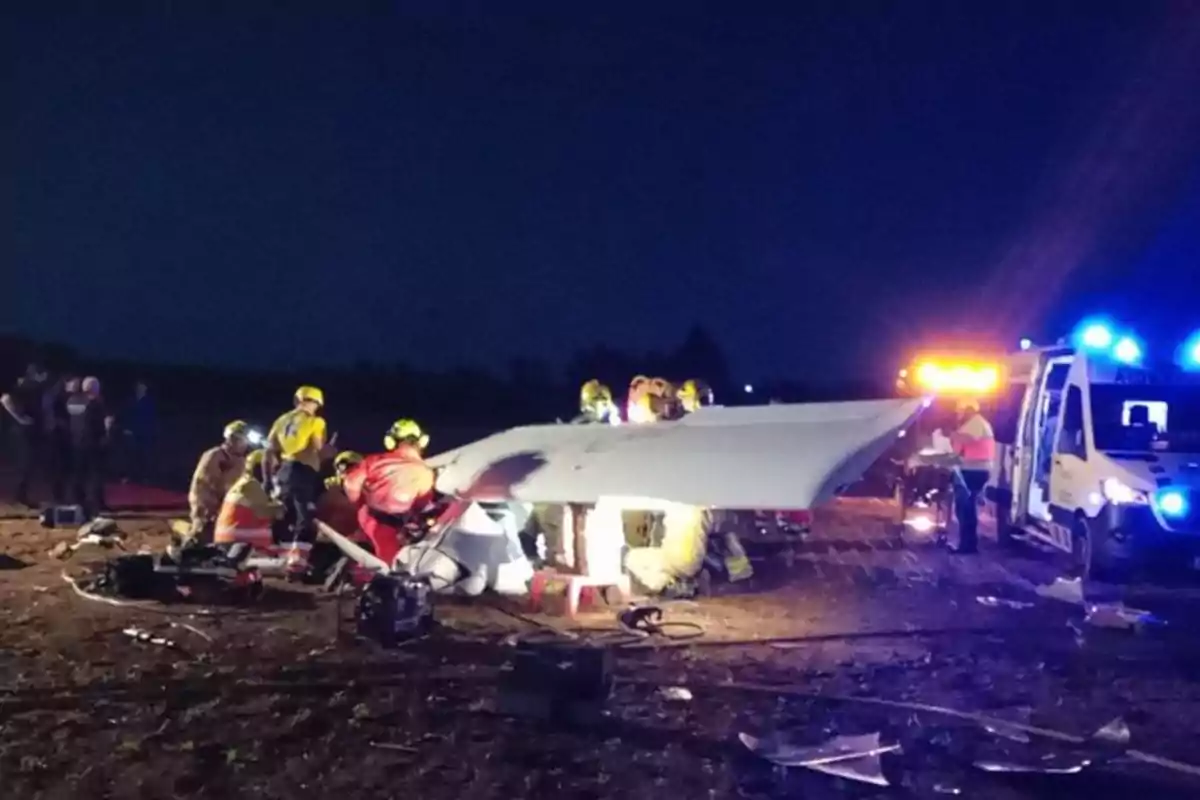 Un grupo de rescatistas trabaja en el lugar de un accidente aéreo durante la noche, con luces de emergencia iluminando la escena.