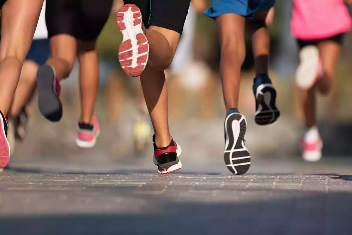 Un grupo de personas haciendo running. En la imagen se les ven los pies y el suelo