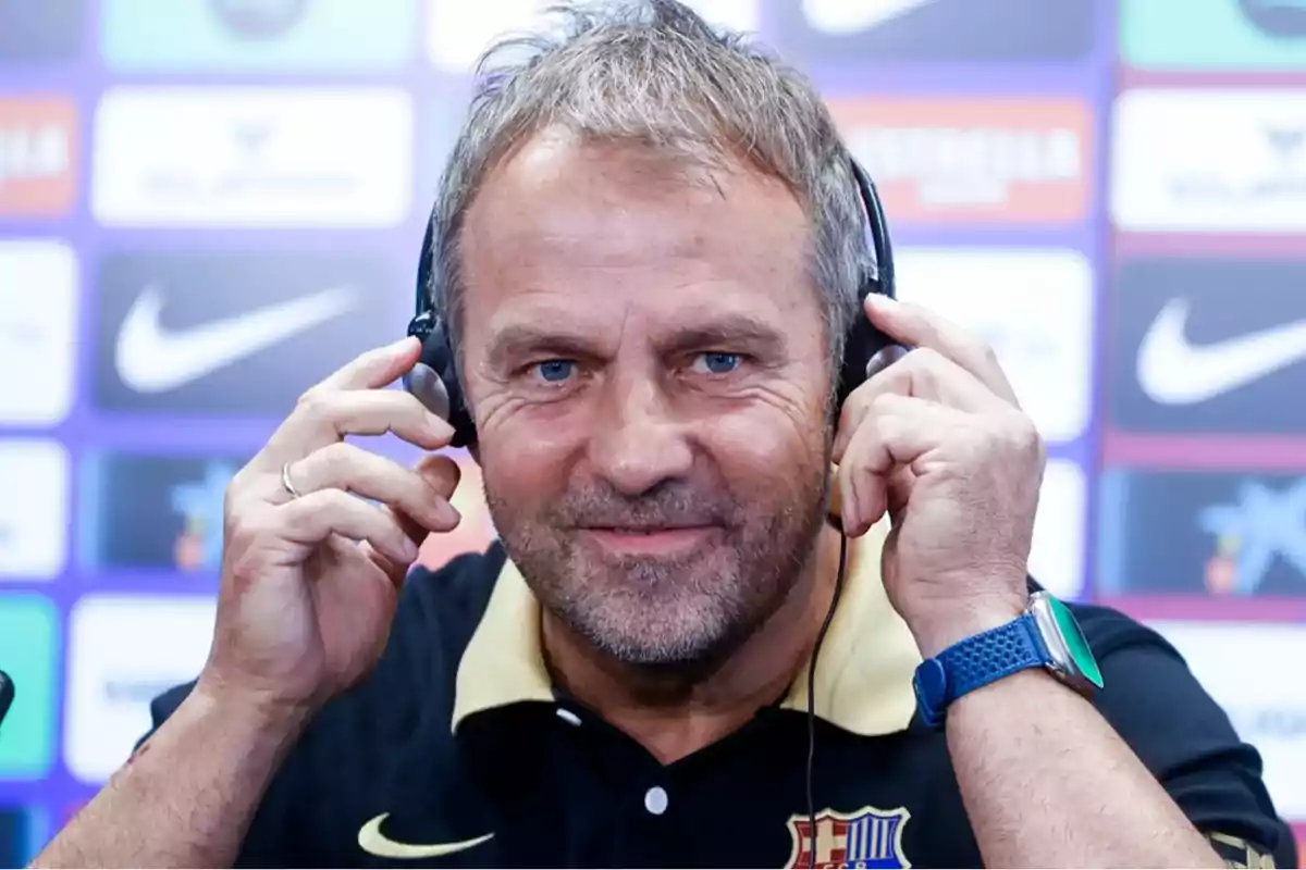 Hombre con auriculares en una conferencia de prensa con fondo de logotipos deportivos.