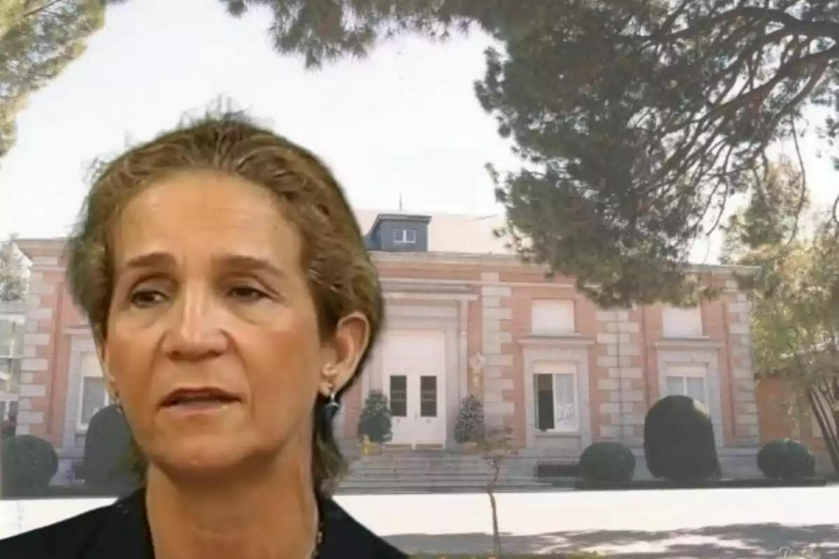 Una mujer de cabello corto y canoso frente a un edificio de ladrillo con árboles alrededor.