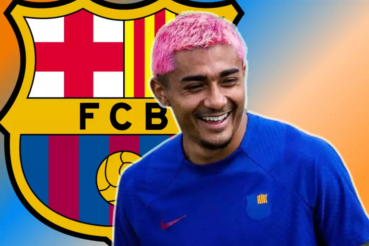 Un jugador de fútbol con cabello teñido de rosa y camiseta azul sonríe frente al escudo del FC Barcelona.