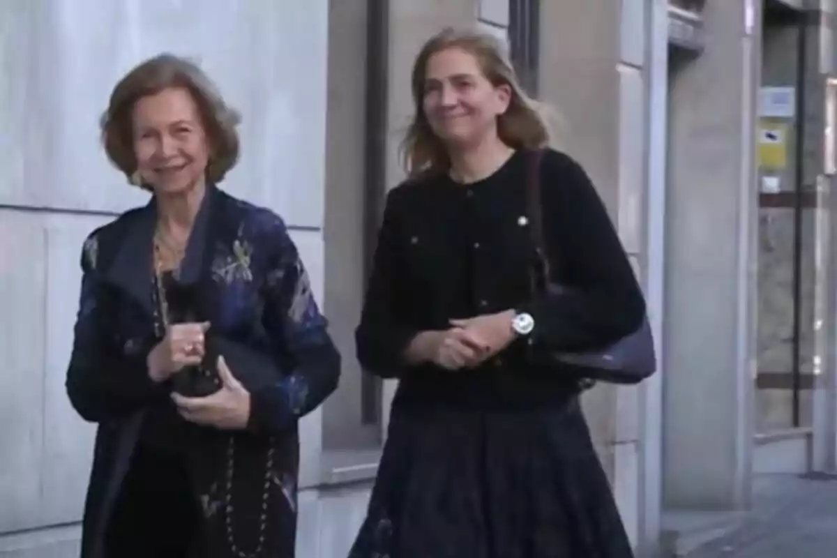 Dos mujeres caminando juntas por la calle, una de ellas con un abrigo oscuro y la otra con un suéter negro.