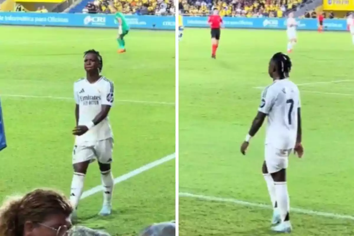 Un jugador de fútbol con el uniforme blanco del Real Madrid camina por el campo durante un partido, con el público y otros jugadores visibles al fondo.