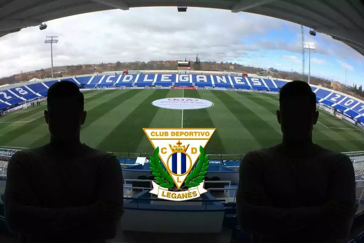 Vista del estadio del Club Deportivo Leganés con dos siluetas de personas en primer plano y el escudo del equipo en el centro.