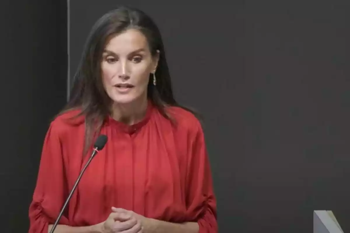 Mujer con blusa roja hablando frente a un micrófono.