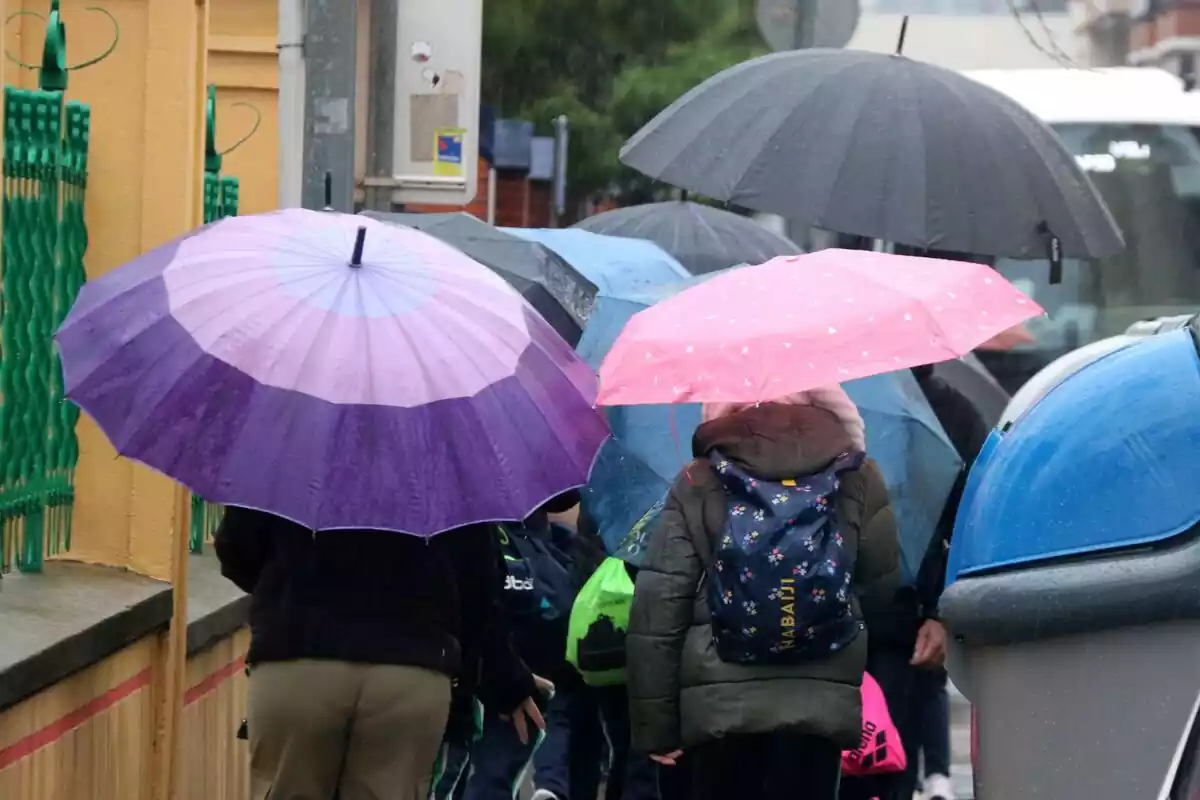 Imagen de varias personas caminando bajo la lluvia con un paraguas