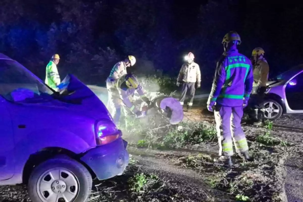 Bomberos trabajando en la escena de un accidente automovilístico nocturno.