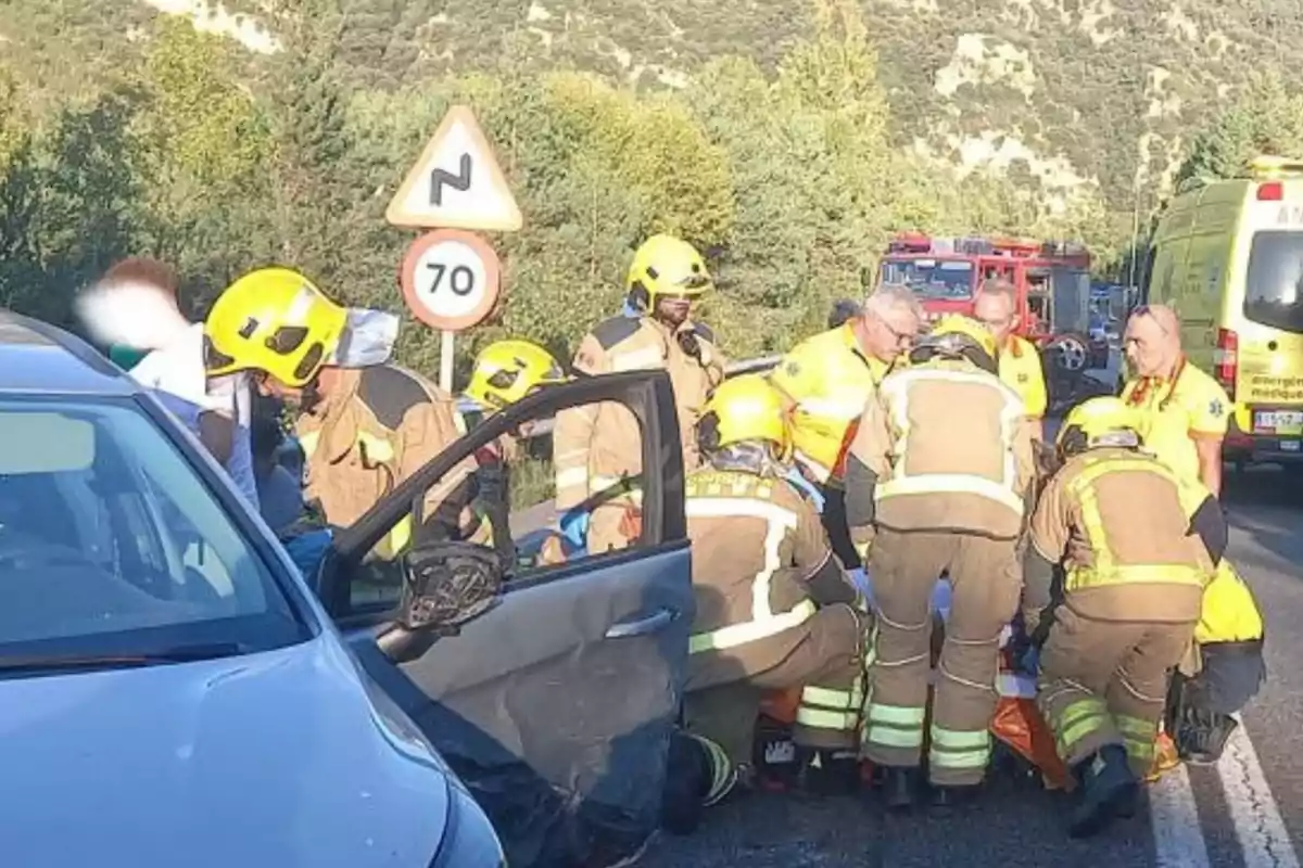 Bomberos y personal de emergencia atienden a una persona herida en un accidente de tráfico en una carretera.