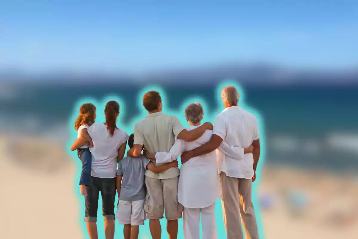 Una familia de varias generaciones abrazándose y mirando al mar en la playa.