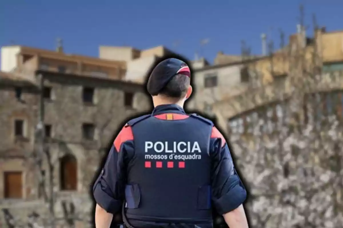 Un agente de los Mossos d'Esquadra de espaldas con un fondo de edificios antiguos.