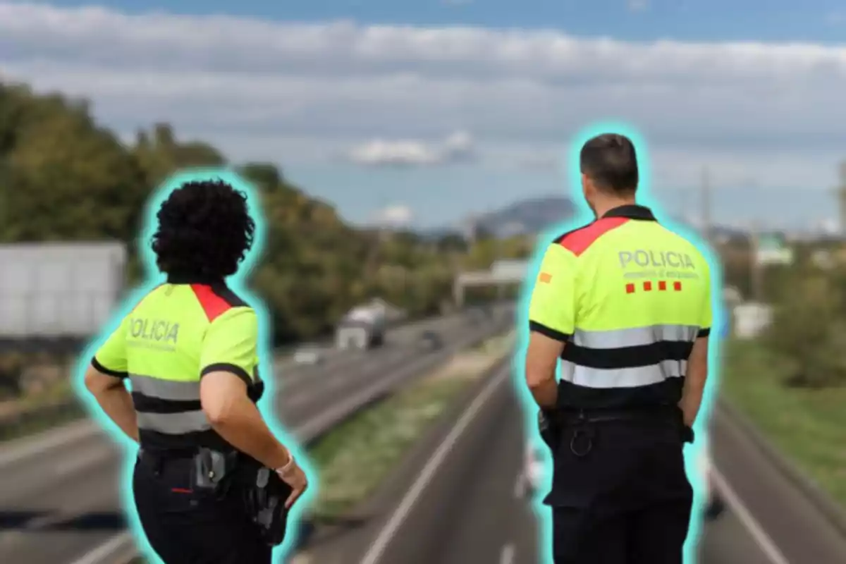 Dos agentes de policía con uniformes reflectantes observan una carretera desde un puente.