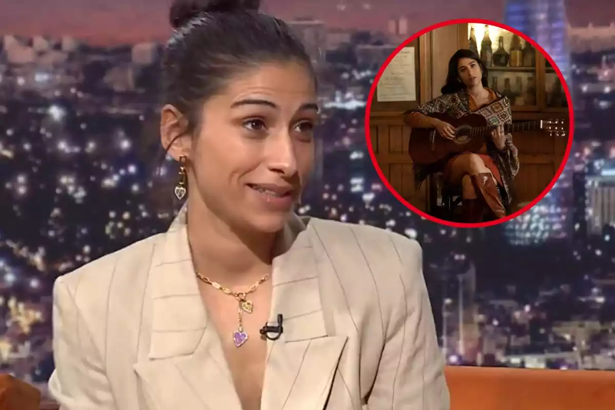 Mujer con cabello recogido y pendientes de corazón en un programa de televisión, con una imagen insertada de ella tocando la guitarra en un ambiente acogedor.