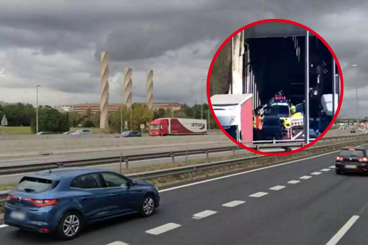 Una carretera con varios vehículos circulando y un camión rojo en el carril central, al fondo se ven tres estructuras altas y retorcidas, el cielo está nublado y hay un círculo rojo que destaca un accidente en un túnel.