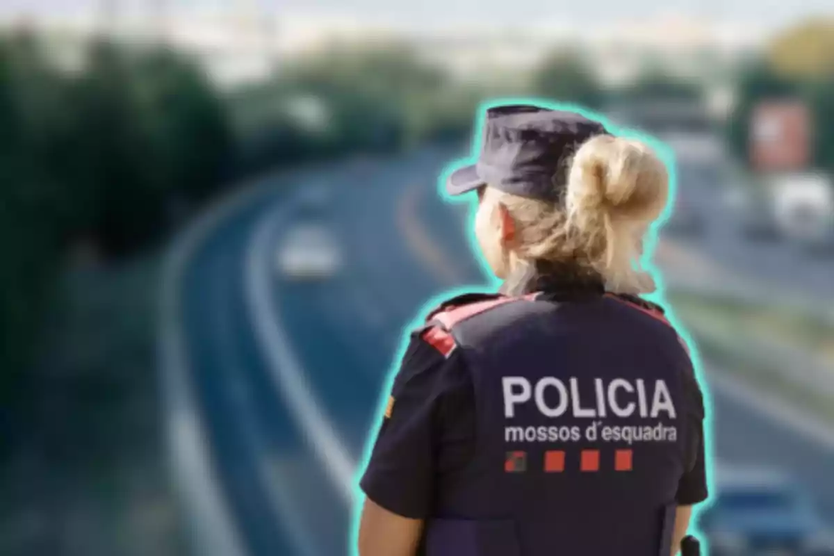 Una agente de policía de los Mossos d'Esquadra de espaldas observando una carretera.