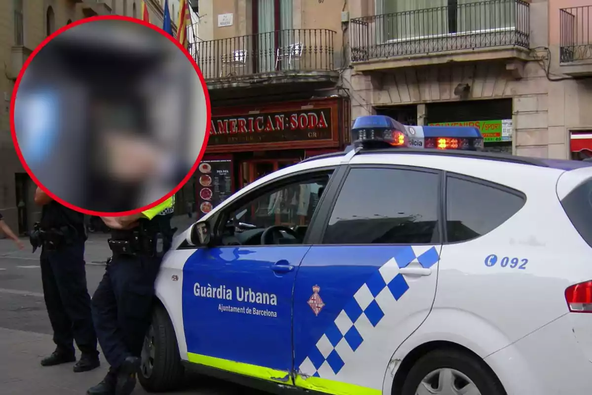 Policías de la Guardia Urbana de Barcelona junto a un coche patrulla estacionado en una calle.