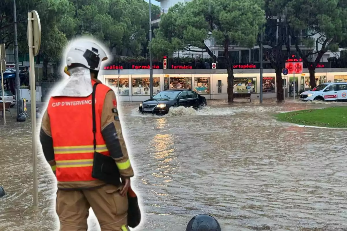 Un bombero observa una calle inundada mientras un coche negro intenta atravesar el agua.