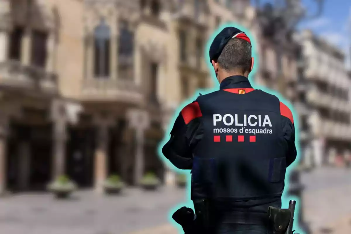 Un agente de policía de los Mossos d'Esquadra de espaldas en una calle urbana.