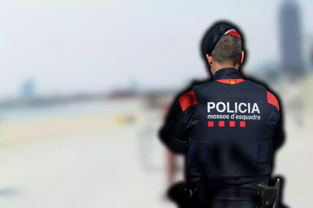 Un agente de los Mossos d'Esquadra de espaldas en una playa.