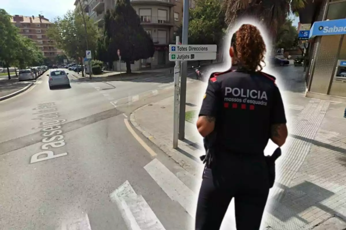 Una agente de policía de los Mossos d'Esquadra de espaldas en una calle de la ciudad, con un cartel de direcciones y un banco en el fondo.