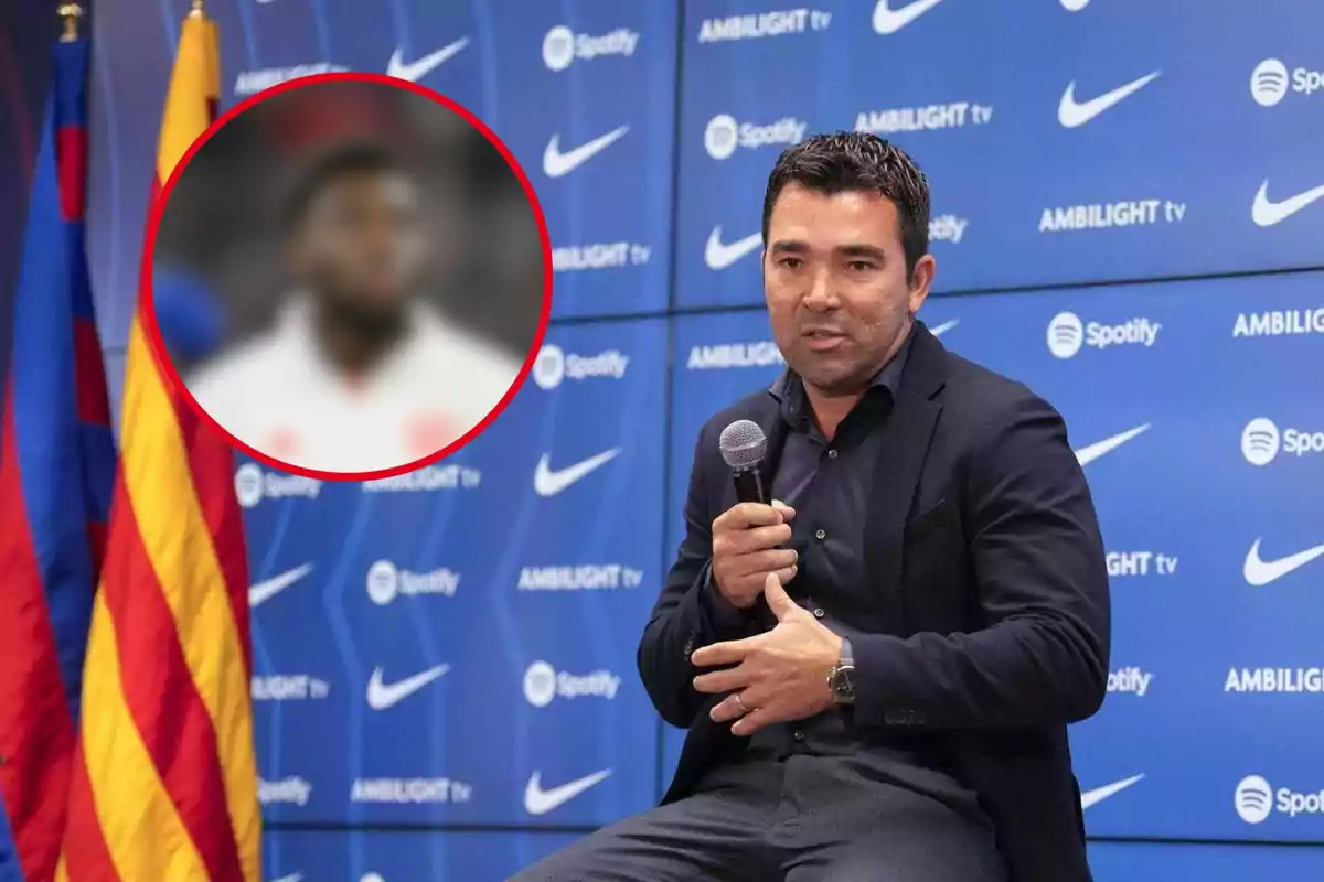 Un hombre con micrófono en una conferencia de prensa frente a un fondo azul con logotipos de Nike y Spotify, junto a una bandera.