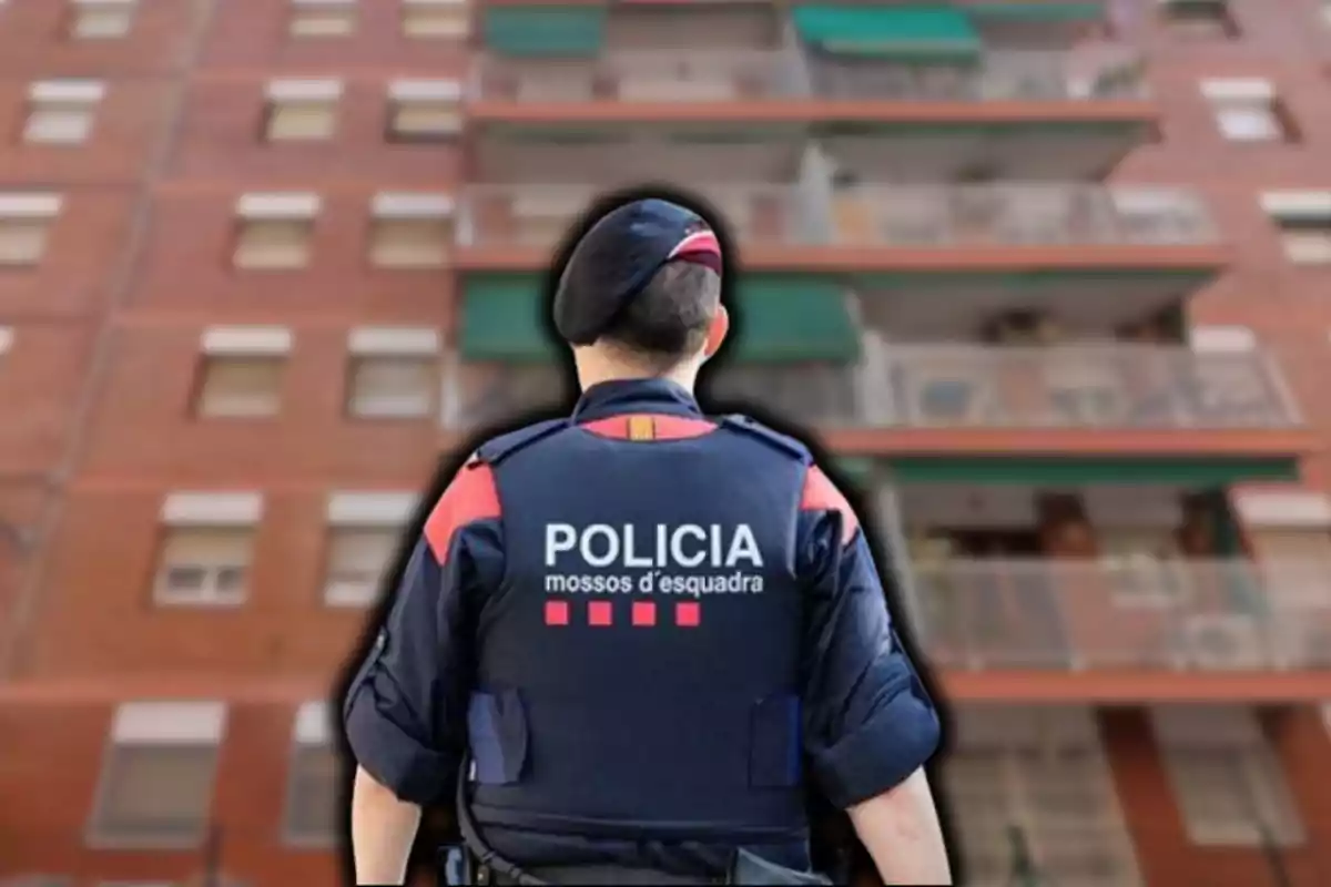 Un agente de policía de espaldas frente a un edificio de apartamentos.