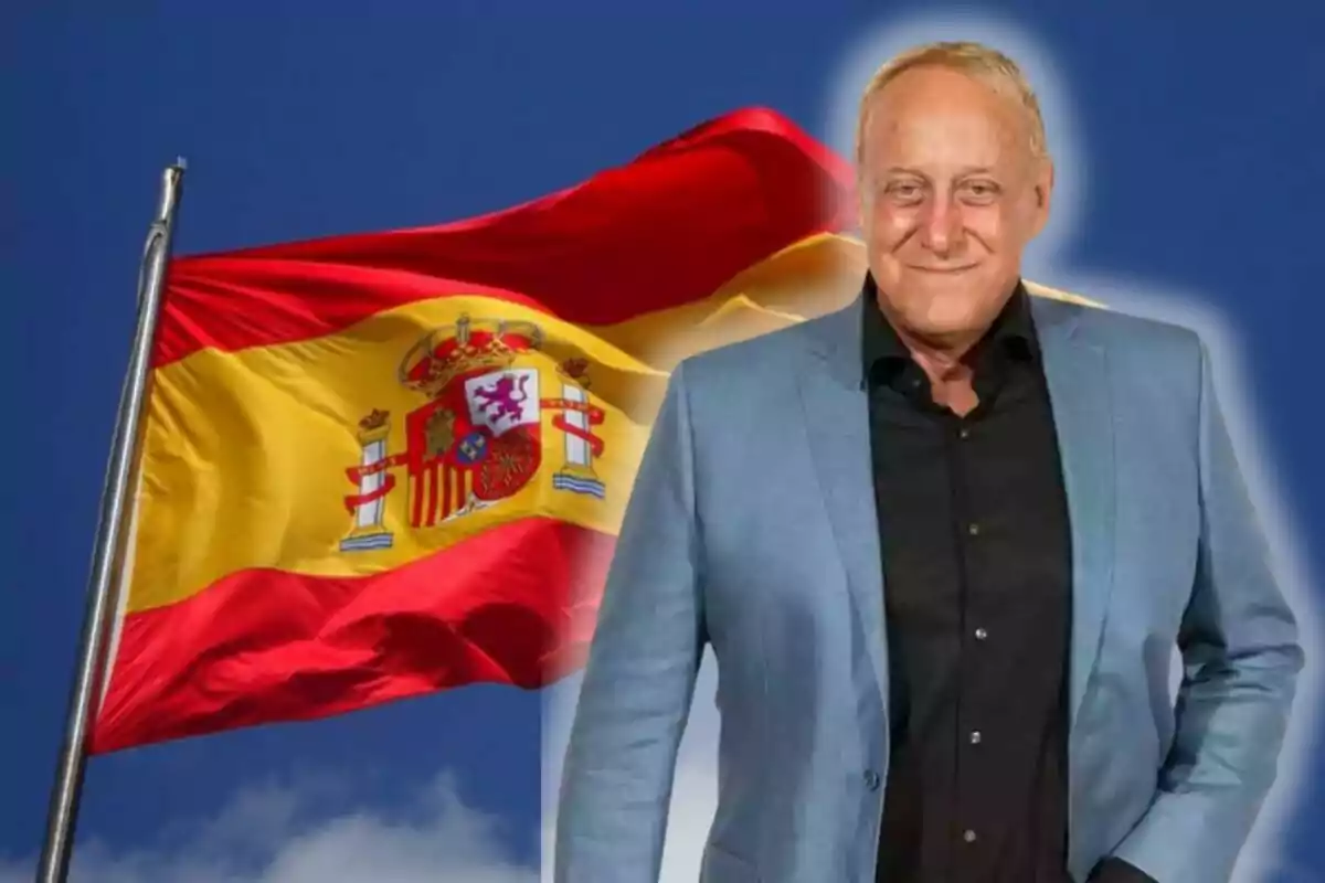 Un hombre con chaqueta azul frente a una bandera de España ondeando.