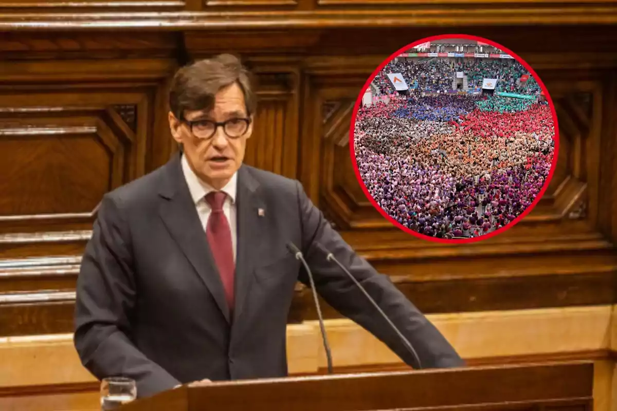 Un hombre con traje y corbata habla en un podio de madera, con una imagen circular superpuesta de una multitud colorida en un estadio.