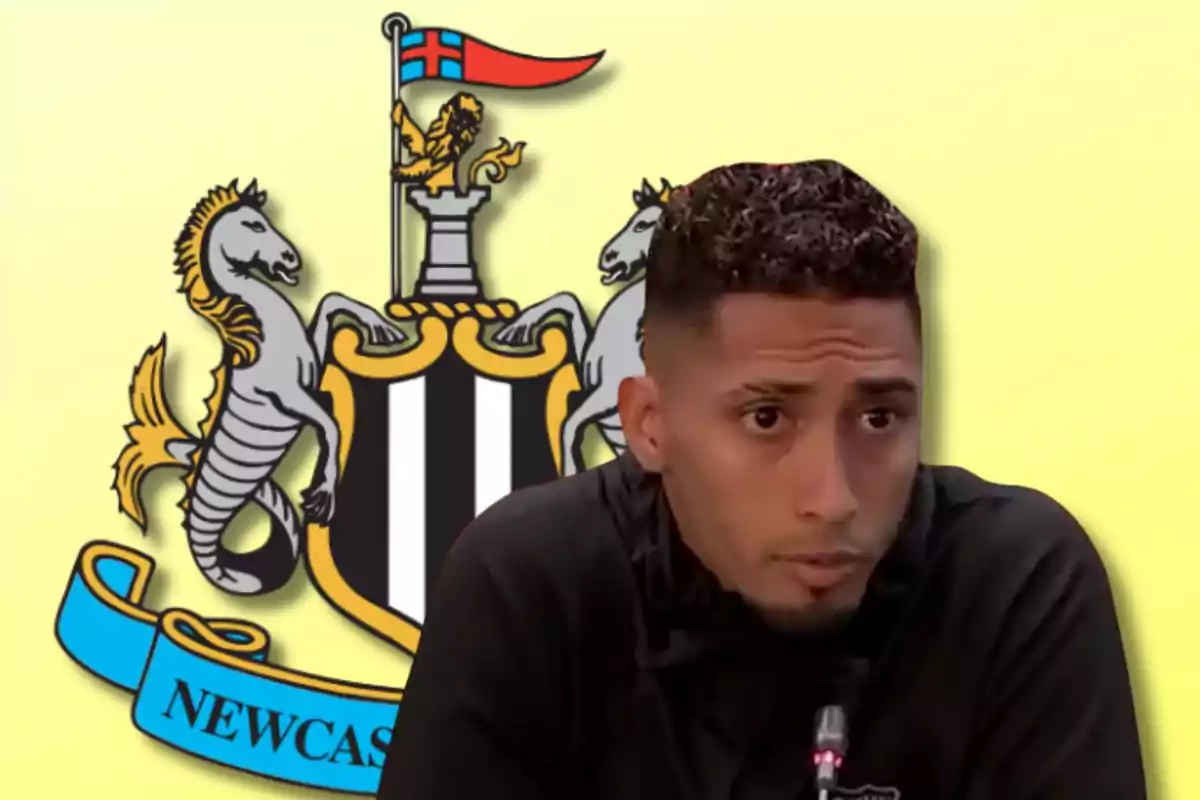 Hombre hablando frente a un micrófono con el escudo del Newcastle United de fondo.