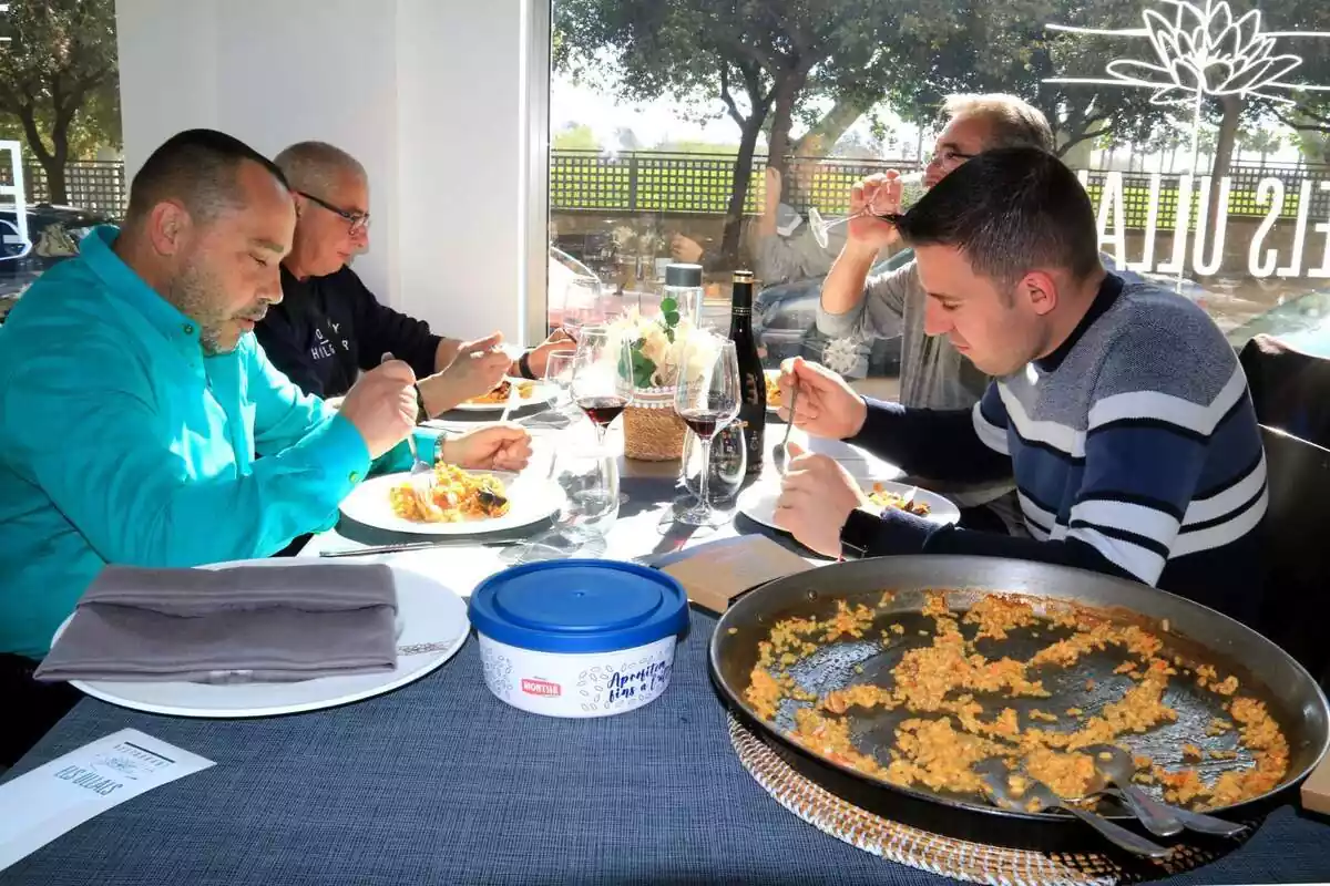 Un grupo de 4 hombres comiendo un arroz en un restaurante