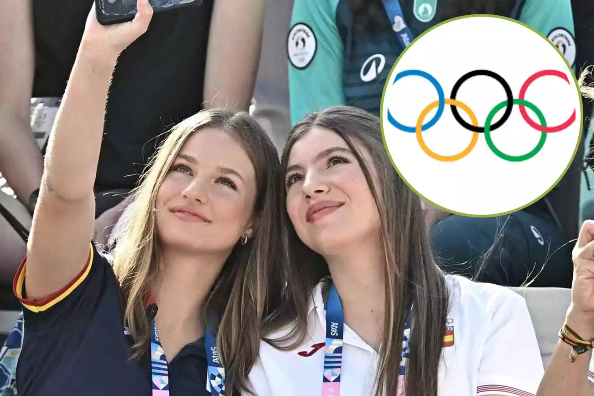 Dos jóvenes se toman una selfie mientras asisten a un evento deportivo, con el logo de los anillos olímpicos superpuesto en la imagen.