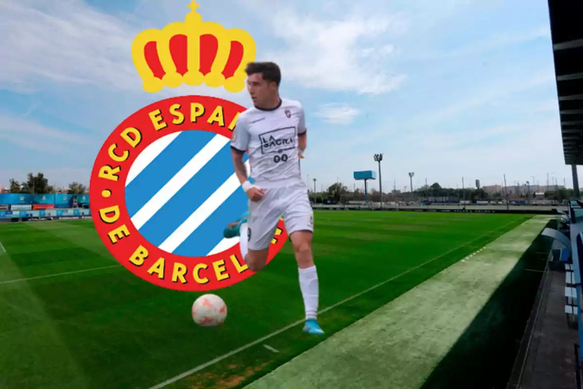 Jugador de fútbol en uniforme blanco corriendo en un campo de fútbol con el escudo del RCD Espanyol de Barcelona en el fondo.