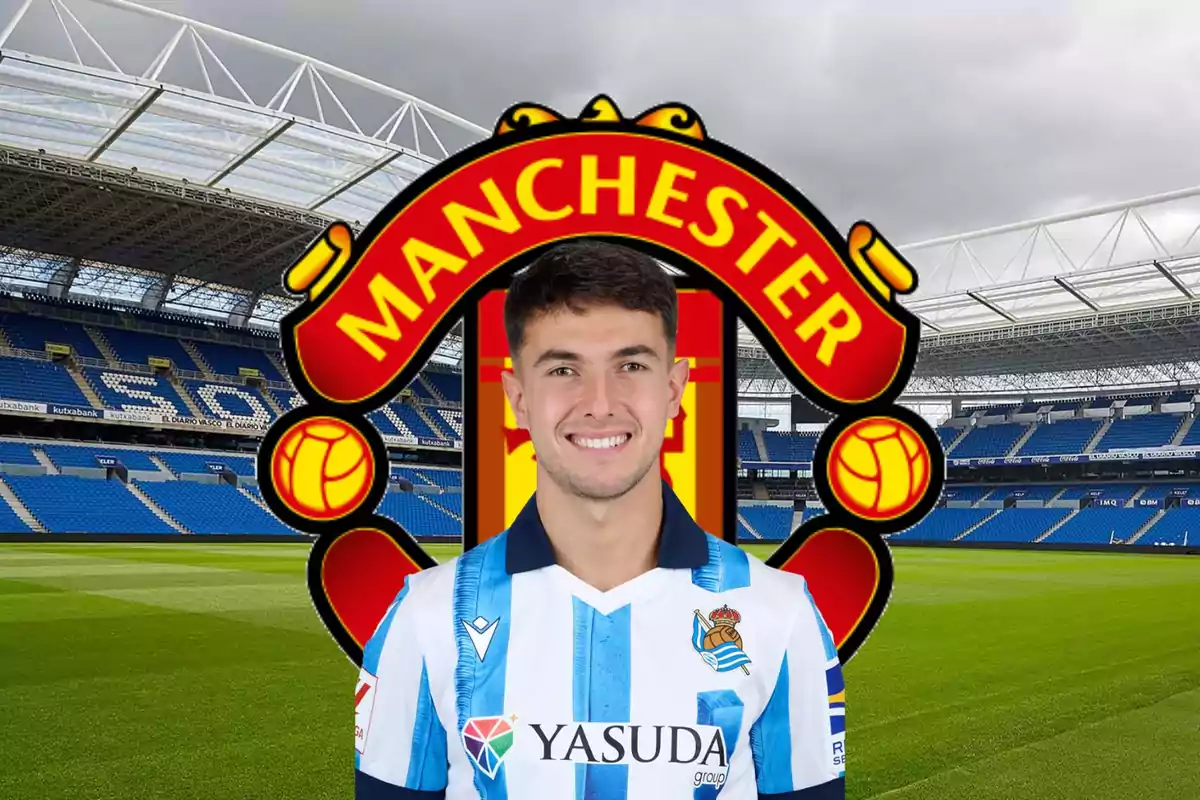 Un jugador de fútbol con la camiseta de la Real Sociedad posando frente al escudo del Manchester United en un estadio.