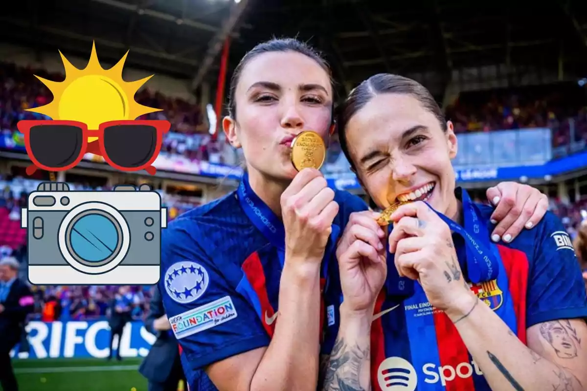 Dos jugadoras de fútbol celebran con medallas de oro en un estadio, una de ellas besa su medalla mientras la otra la muerde, ambas llevan camisetas del FC Barcelona y tienen medallas colgadas al cuello, hay un emoji de sol con gafas de sol y una cámara superpuesto en la imagen.