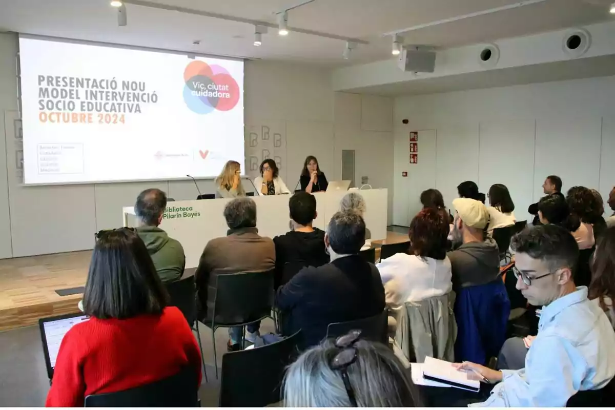 Personas asistiendo a una presentación sobre un nuevo modelo de intervención socioeducativa en la Biblioteca Pilarin Bayés.