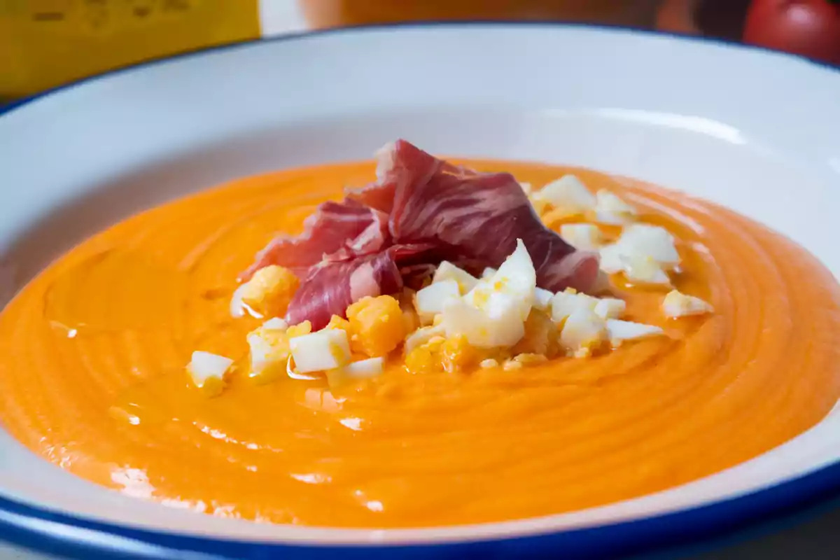 Un plato de salmorejo con trozos de huevo duro y jamón serrano.