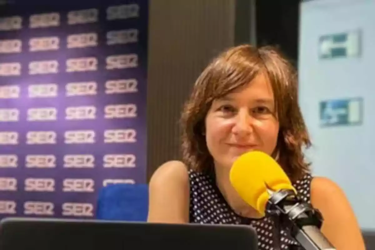 Persona hablando en un micrófono amarillo en un estudio de radio con el logo de la cadena SER en el fondo.