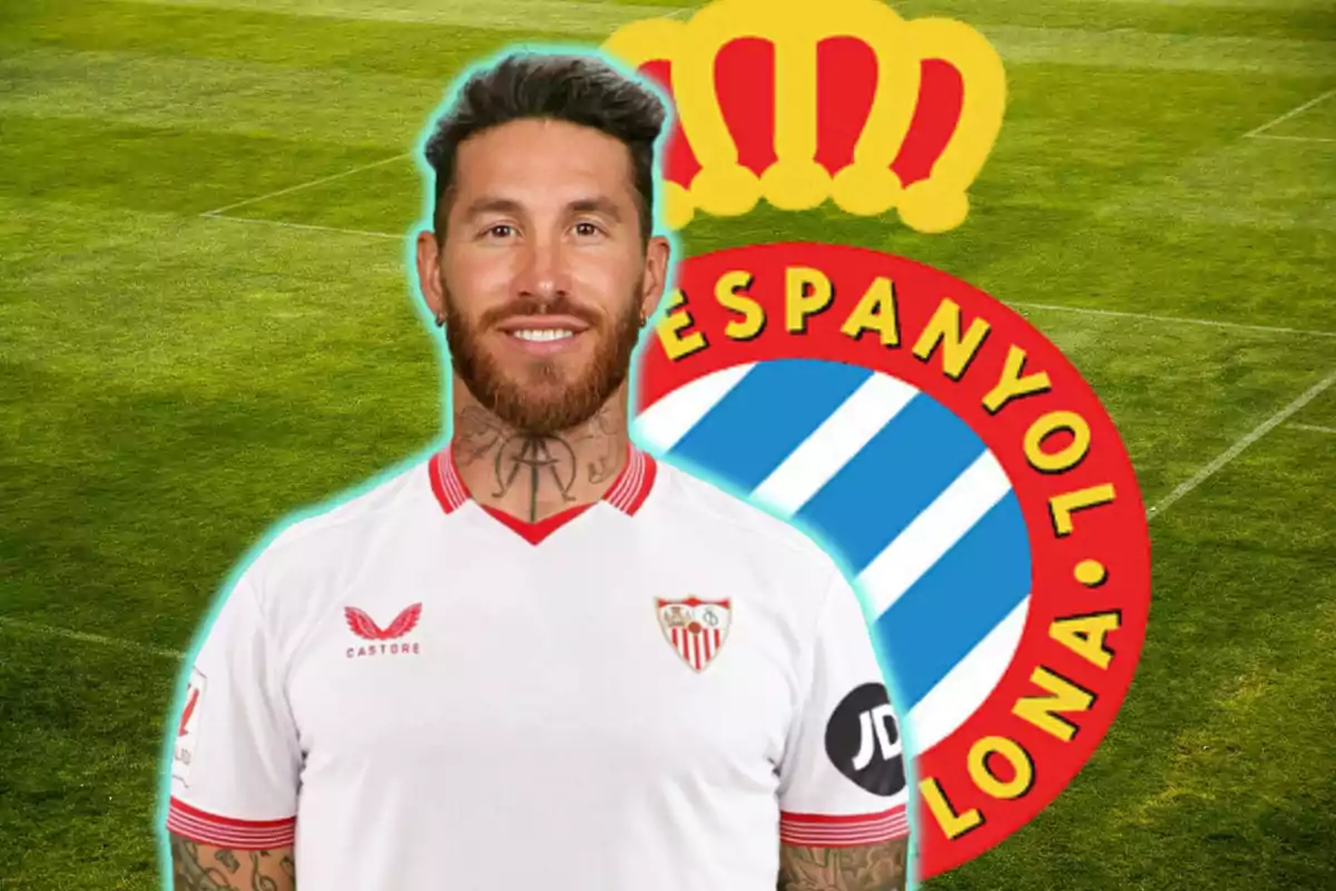 Un jugador de fútbol con la camiseta del Sevilla FC posando frente al escudo del RCD Espanyol en un campo de fútbol.