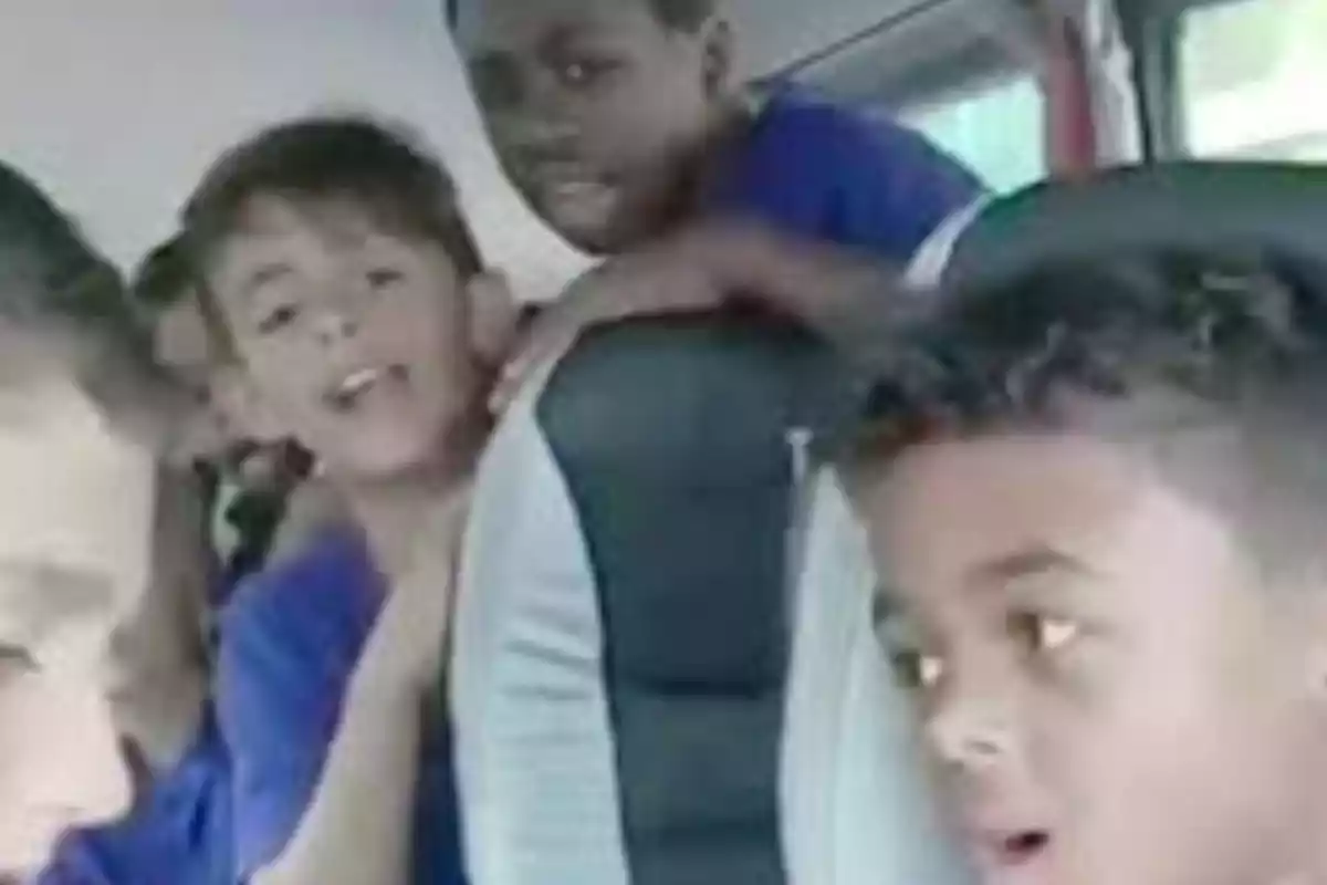 Un grupo de niños en un autobús, algunos de ellos parecen estar cantando o hablando animadamente.